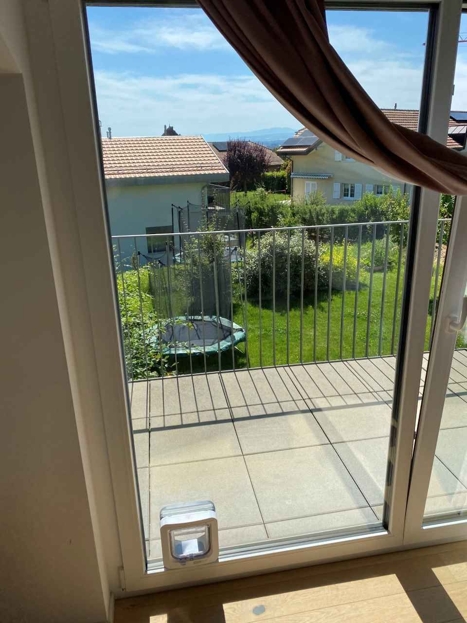 Une porte coulissante en verre menant à un balcon avec un trampoline en arrière-plan