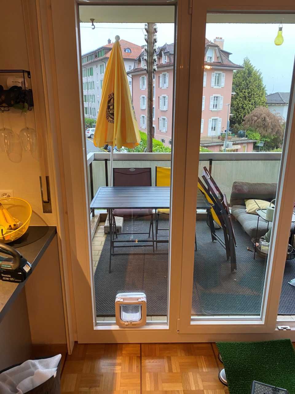 Une porte coulissante en verre donnant sur un balcon avec une table et des chaises
