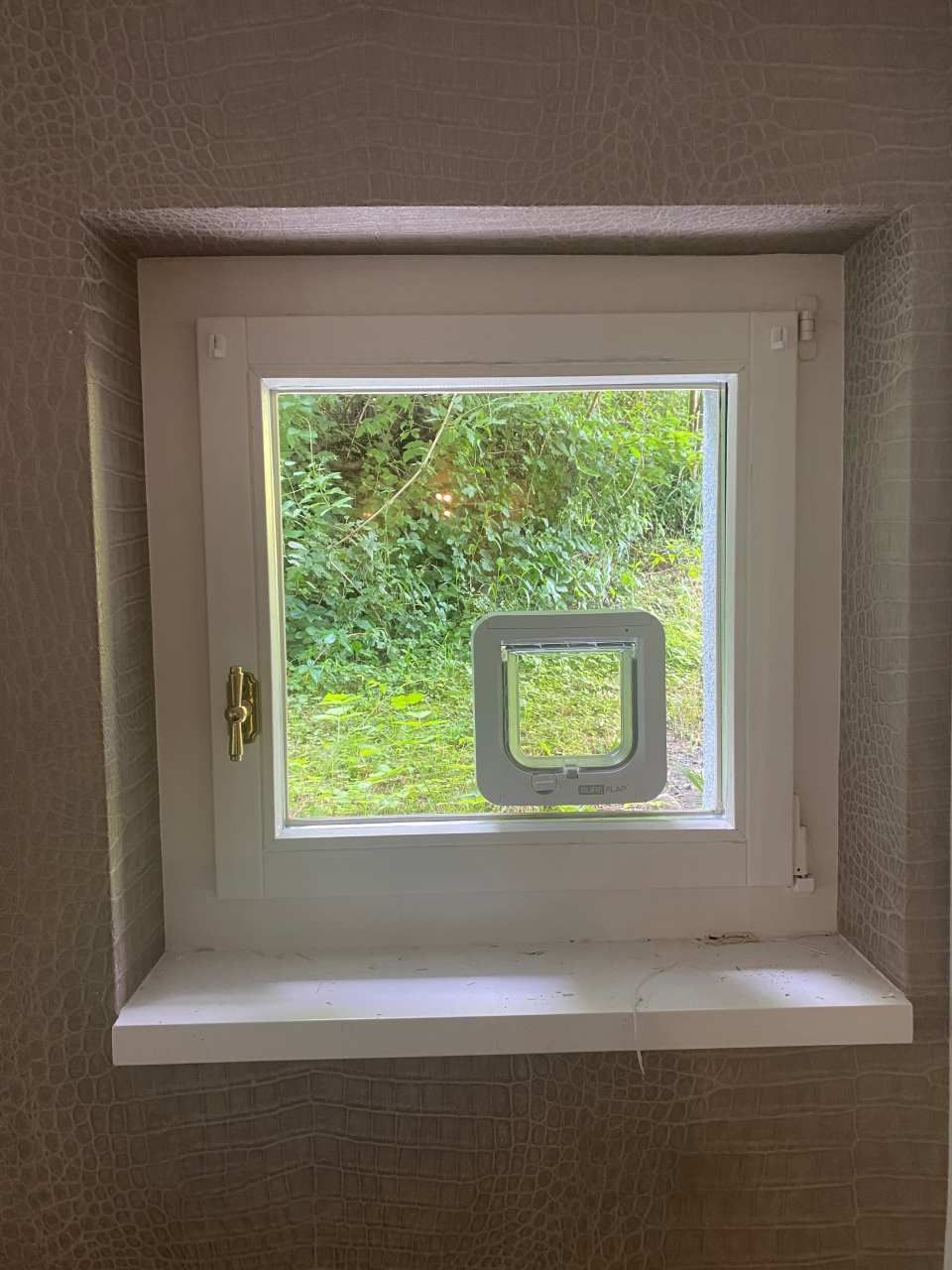 Une fenêtre blanche avec une chatière à l'intérieur.