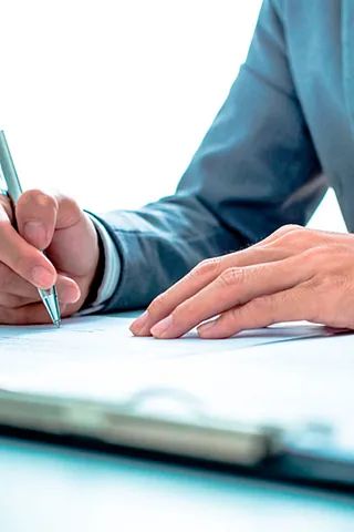 Una persona está escribiendo en un trozo de papel con un bolígrafo.
