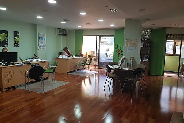 Una habitación grande con suelo de madera, mesas y sillas.