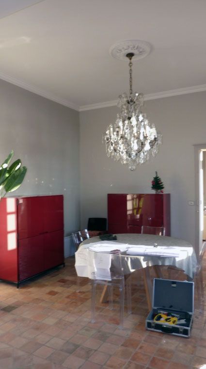 Pièce avec des armoires rouges, une table avec des chaises en plastique et un lustre en cristal.