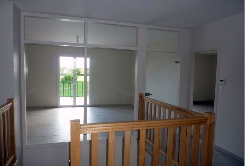 Vue intérieure d'un palier avec une rambarde en bois, donnant sur une pièce avec balcon.