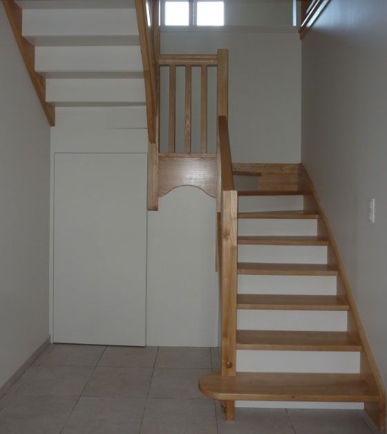 Escalier en bois avec contremarches blanches, menant au deuxième étage.