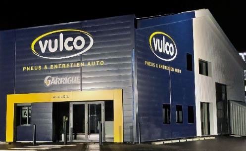 L'extérieur de l'atelier de réparation automobile Vulco présente des accents jaunes et une façade bleue.
