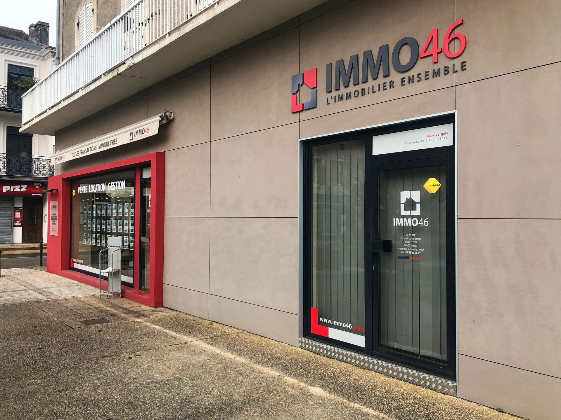 Deux devantures commerciales : une agence immobilière avec un auvent et une enseigne rouges ; juste à côté, l’enseigne Immo46.