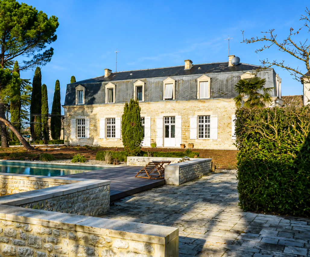 Maison de maître en pierre et mansardée à Cahors avec piscine et aménagements paysagers.