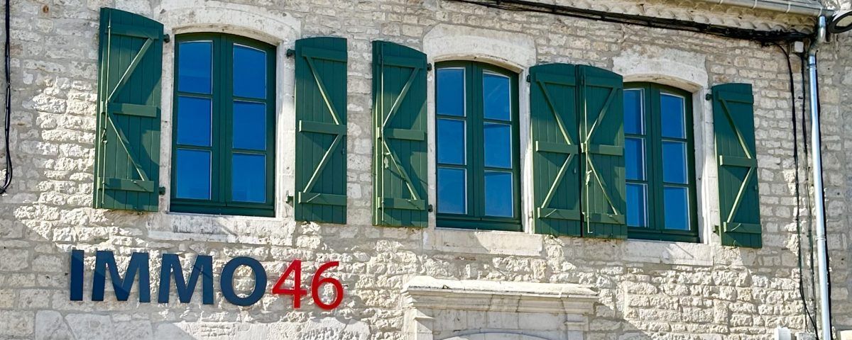 Bâtiment avec des volets verts et le nom IMMO46  inscrit sur le mur.