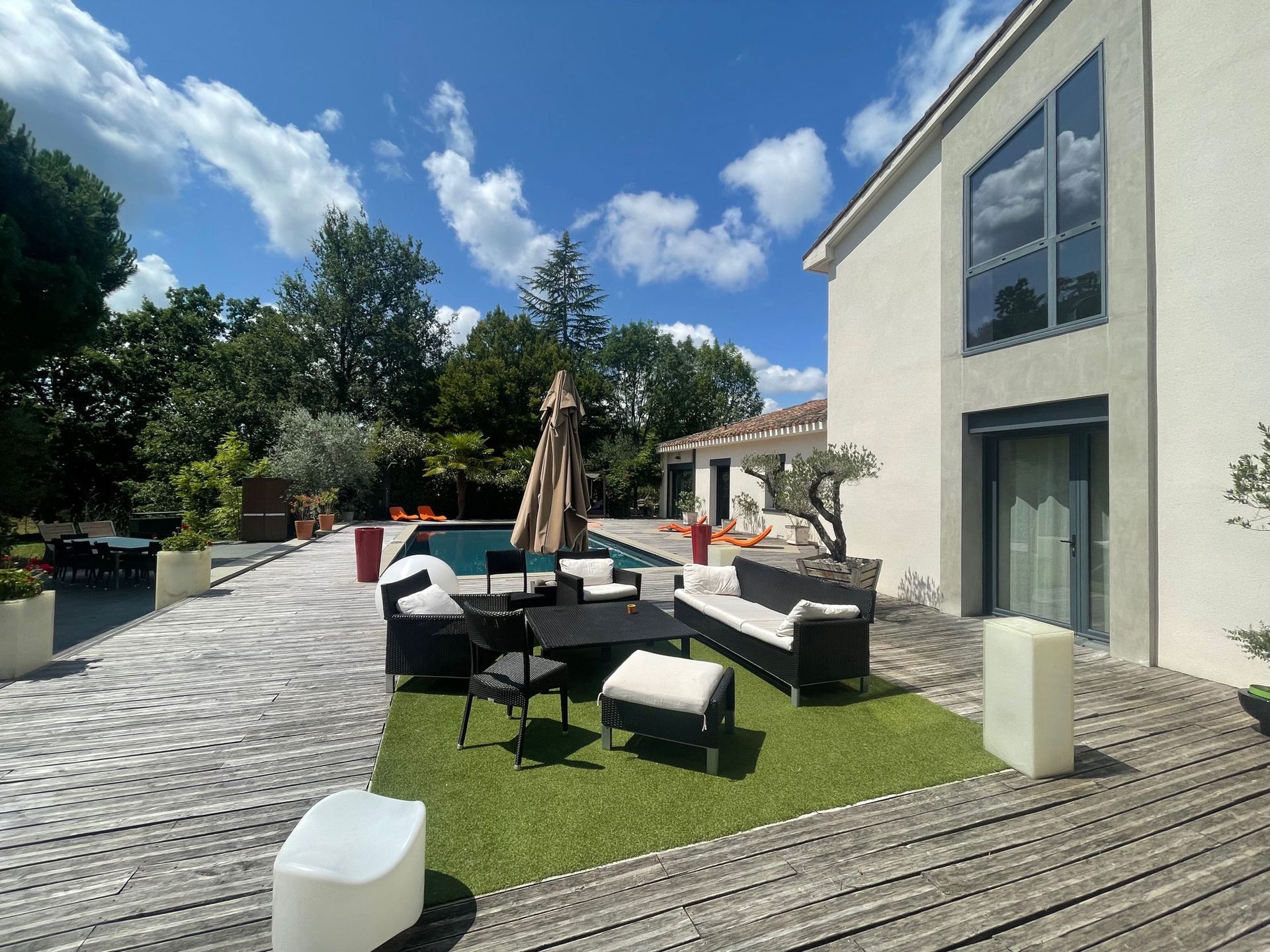Terrasse extérieure meublée, petite piscine et maison moderne sous un ciel bleu.