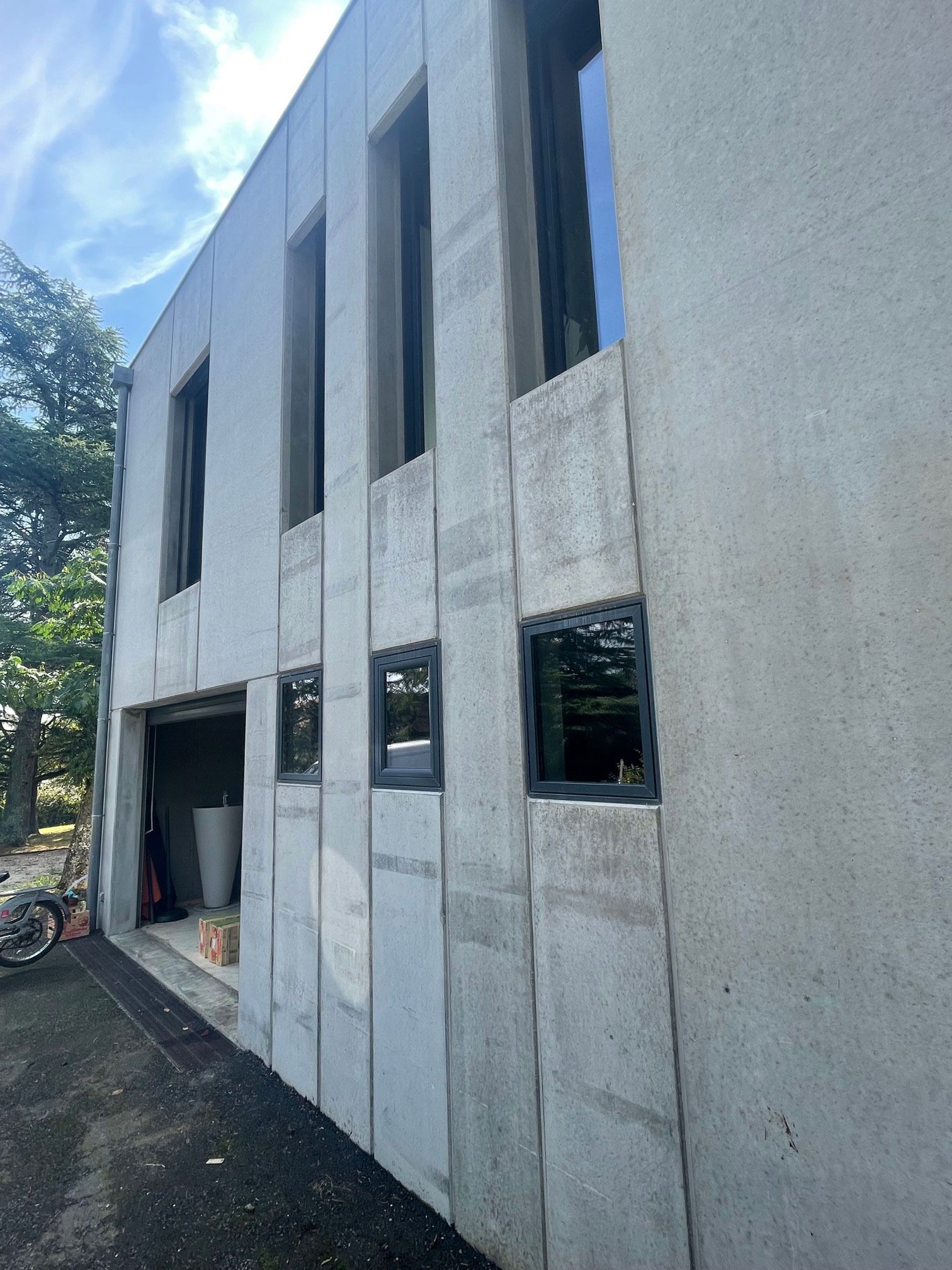 Bâtiment en béton gris avec des ouvertures de fenêtres verticales.
