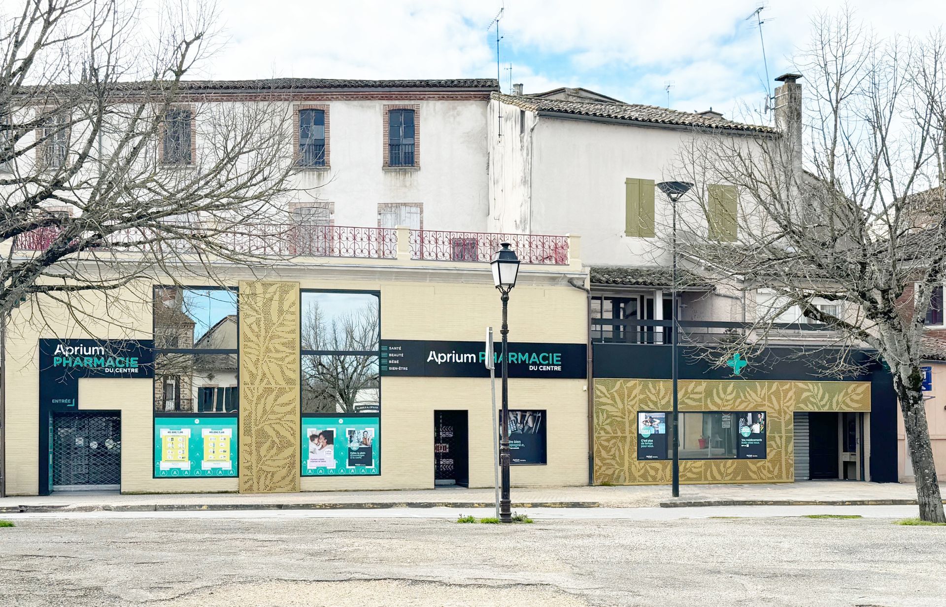 Bâtiment de pharmacie avec façade moderne, briques, fenêtres, et bâtiment traditionnel à l'arrière.