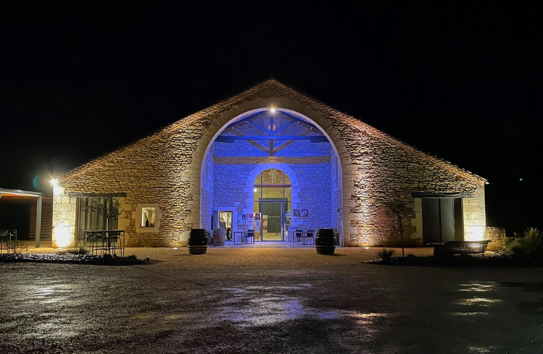 Bâtiment en pierre illuminé en bleu et blanc la nuit.