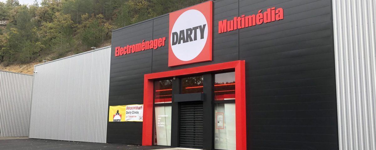 Magasin d'électronique Darty, avec façade noire, touches de rouge et grand logo.