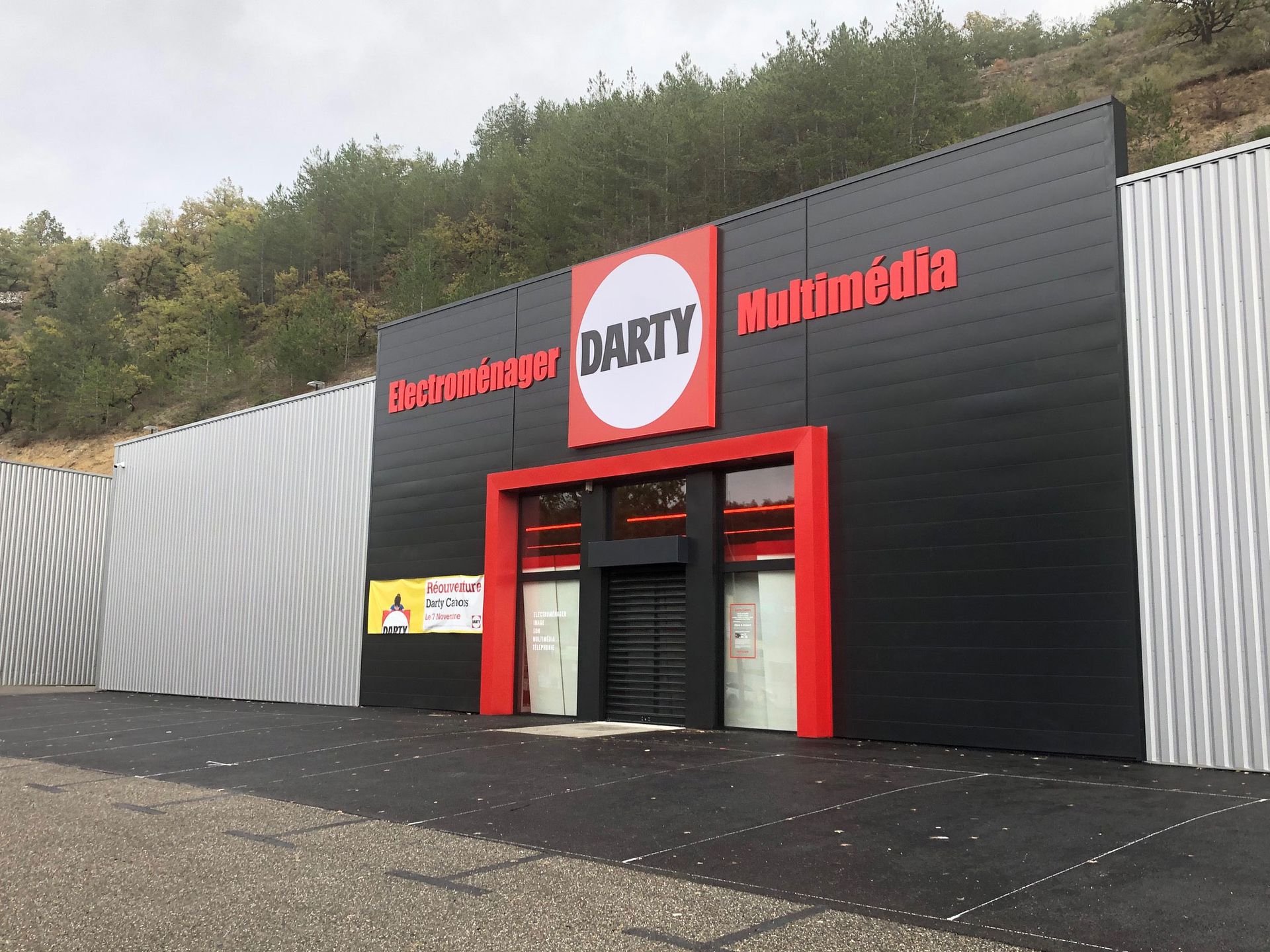 Façade du magasin Darty Multimedia avec une enseigne et une entrée rouges et noires. Murs latéraux métalliques.