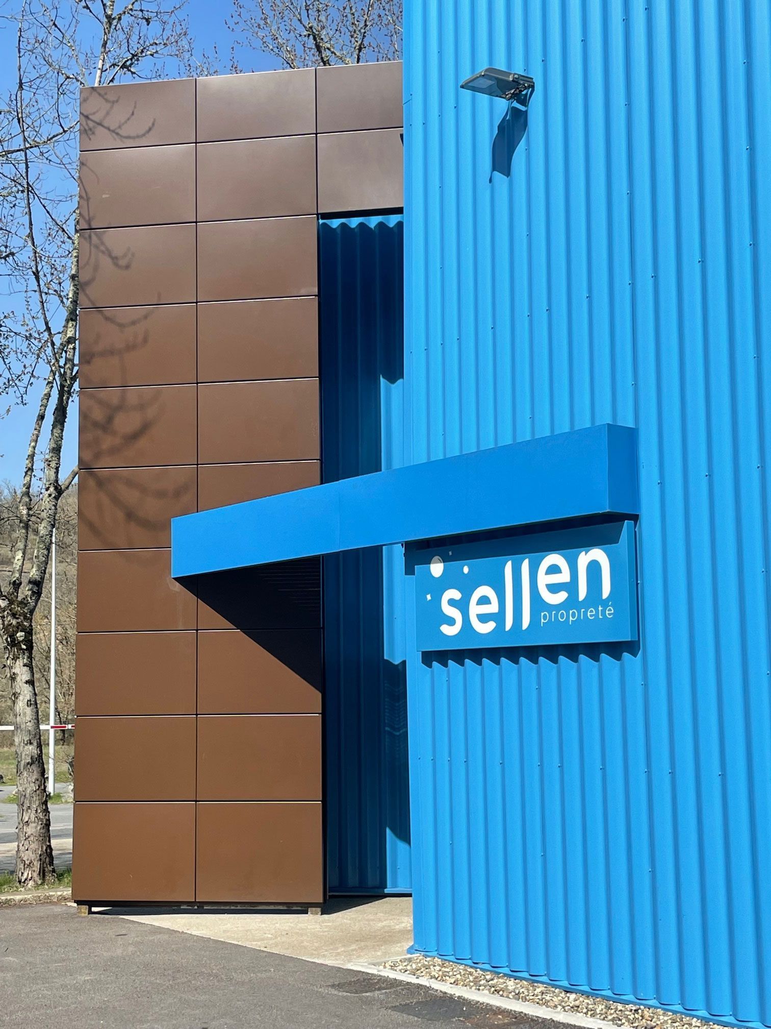 Bâtiment brun et bleu avec enseigne « sellen », auvent bleu. Bardage en tôle ondulée et plate.