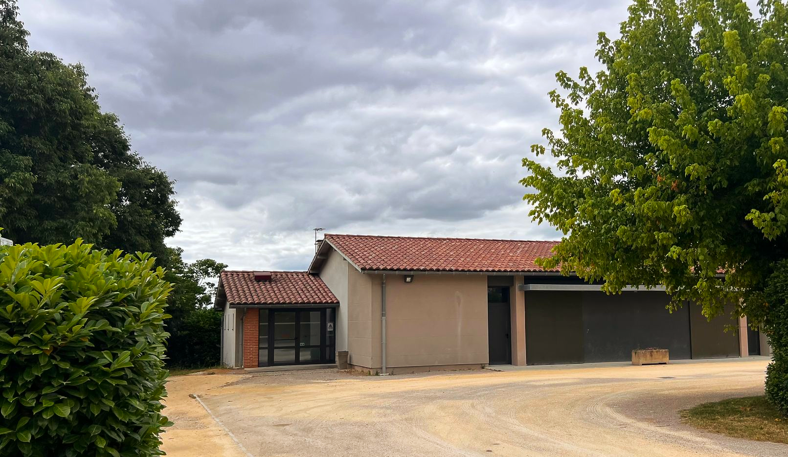 Bâtiment beige avec un toit de tuiles en terre cuite et un ciel bleu.