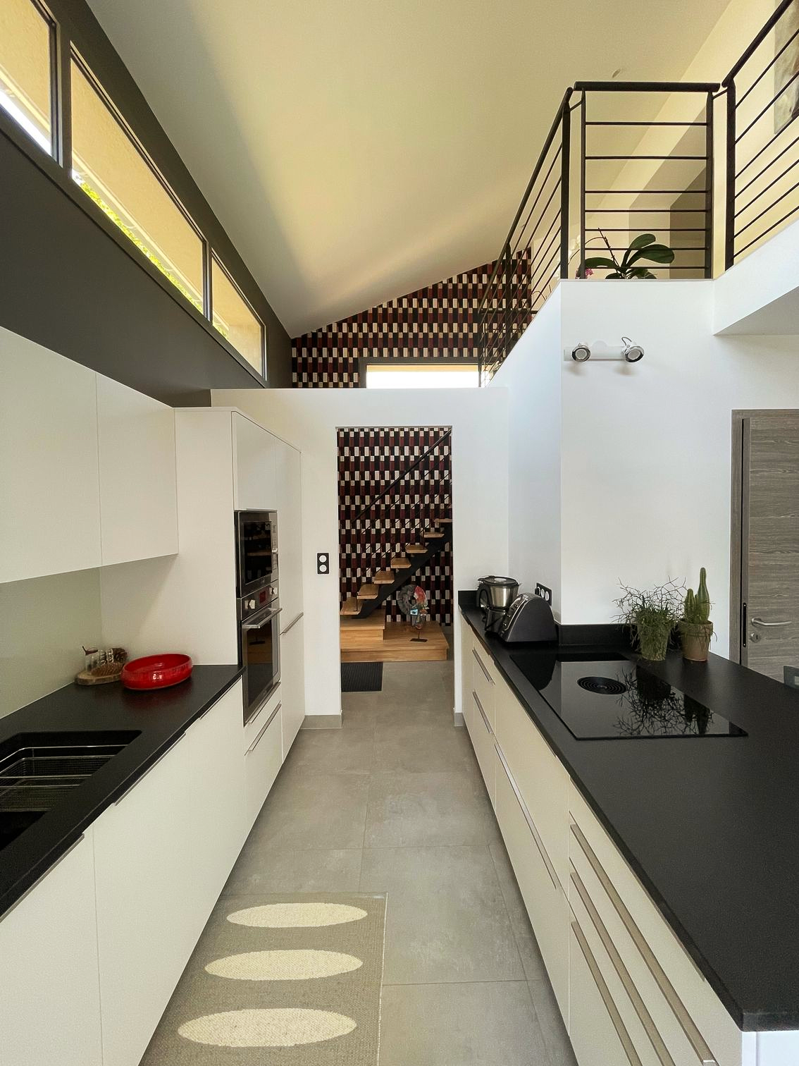 Terrasse avec pergola, table, chaises et piscine. La maison a une façade blanche.