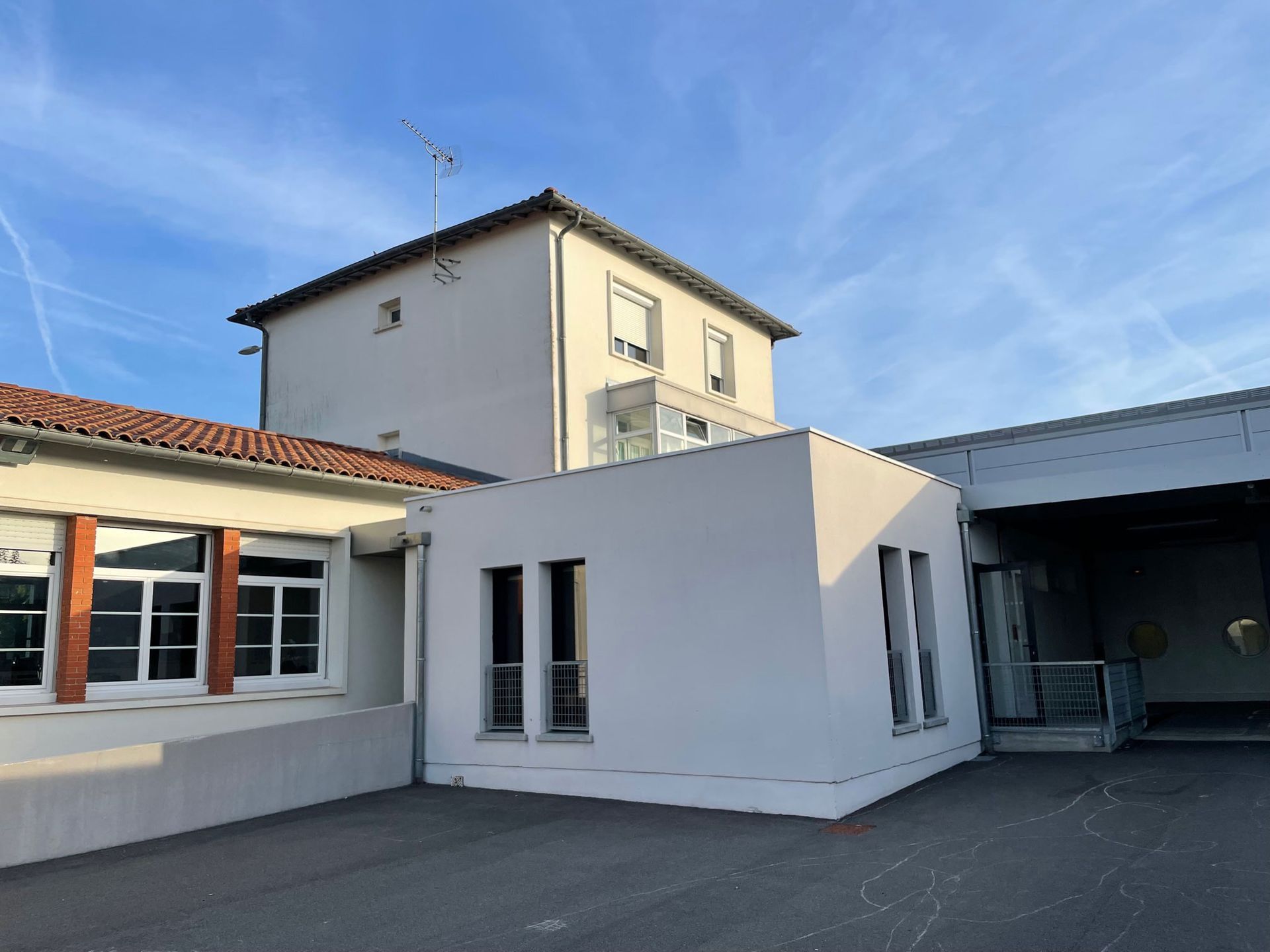 Des bâtiments blancs et beiges avec des fenêtres sous un ciel bleu. Certains sont mitoyens, et l'un d'eux a un toit de tuiles rouges.