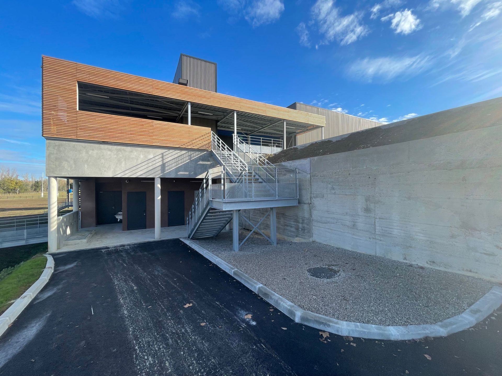 Bâtiment avec un escalier métallique, des murs en béton et un toit sous un ciel bleu.