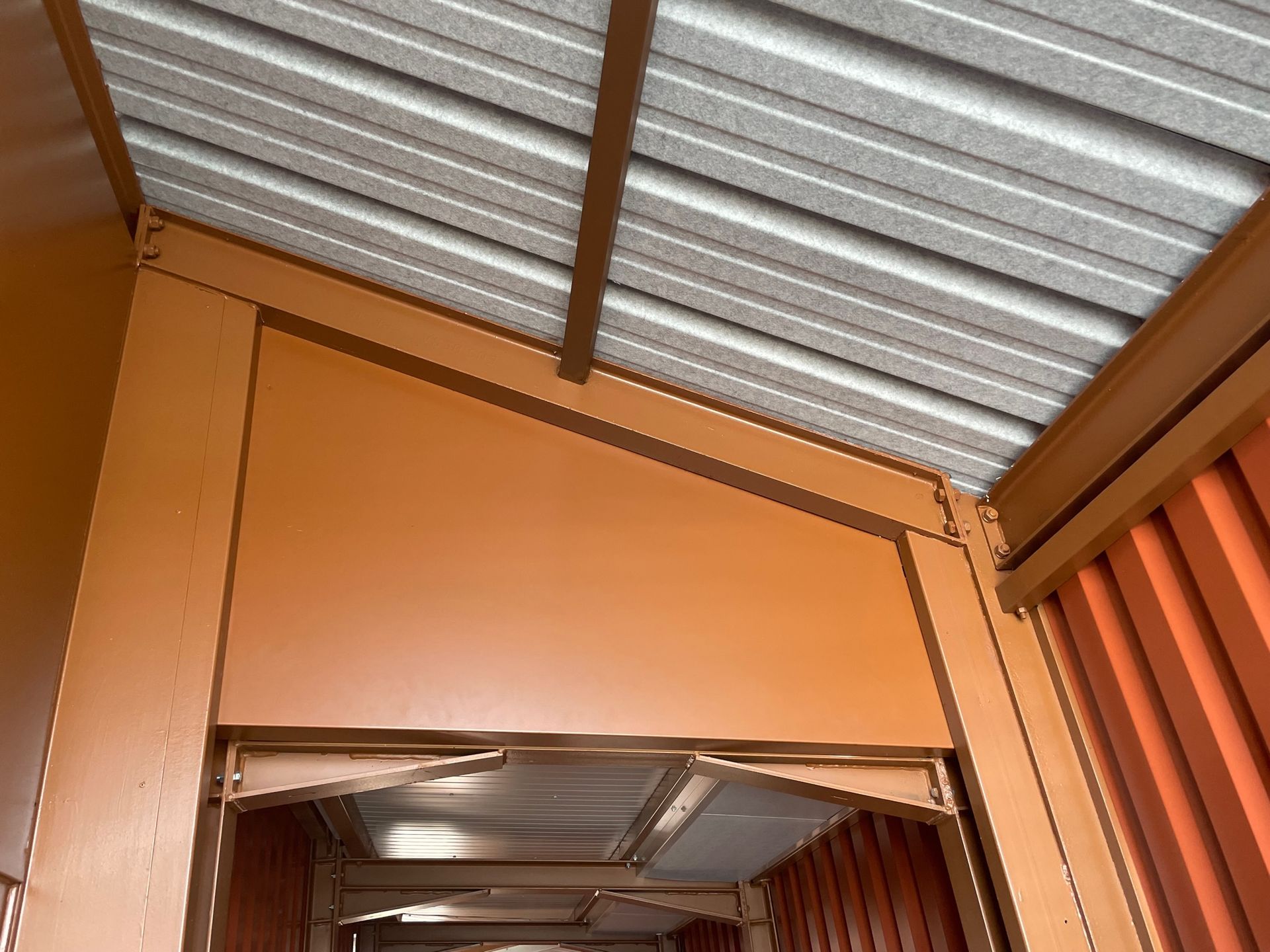 Auvent en métal brun avec toit en tôle ondulée. Murs orange et aperçu de l'intérieur.