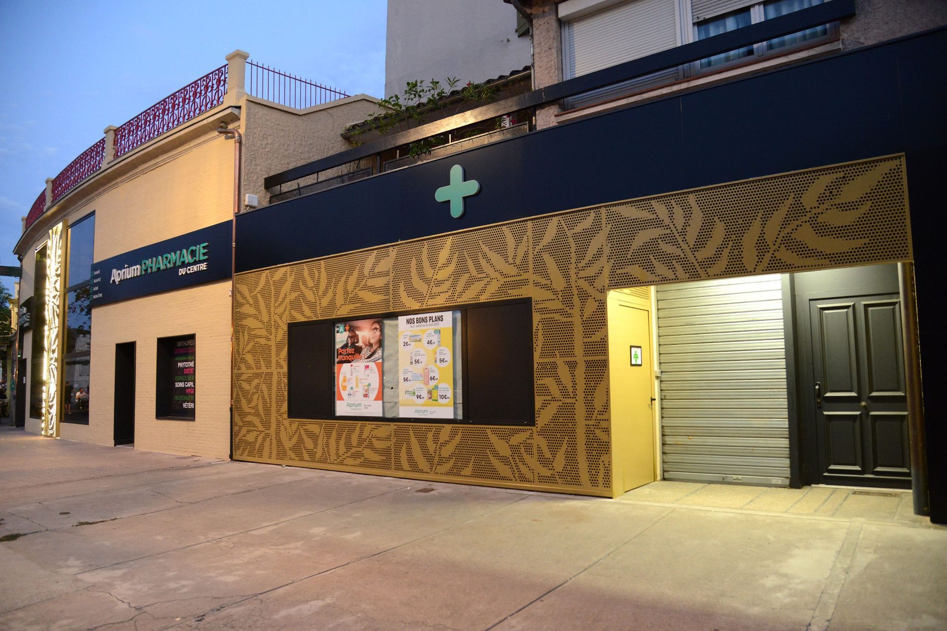 Extérieur d'un théâtre à la façade noire et or. On y voit des affiches et une porte.