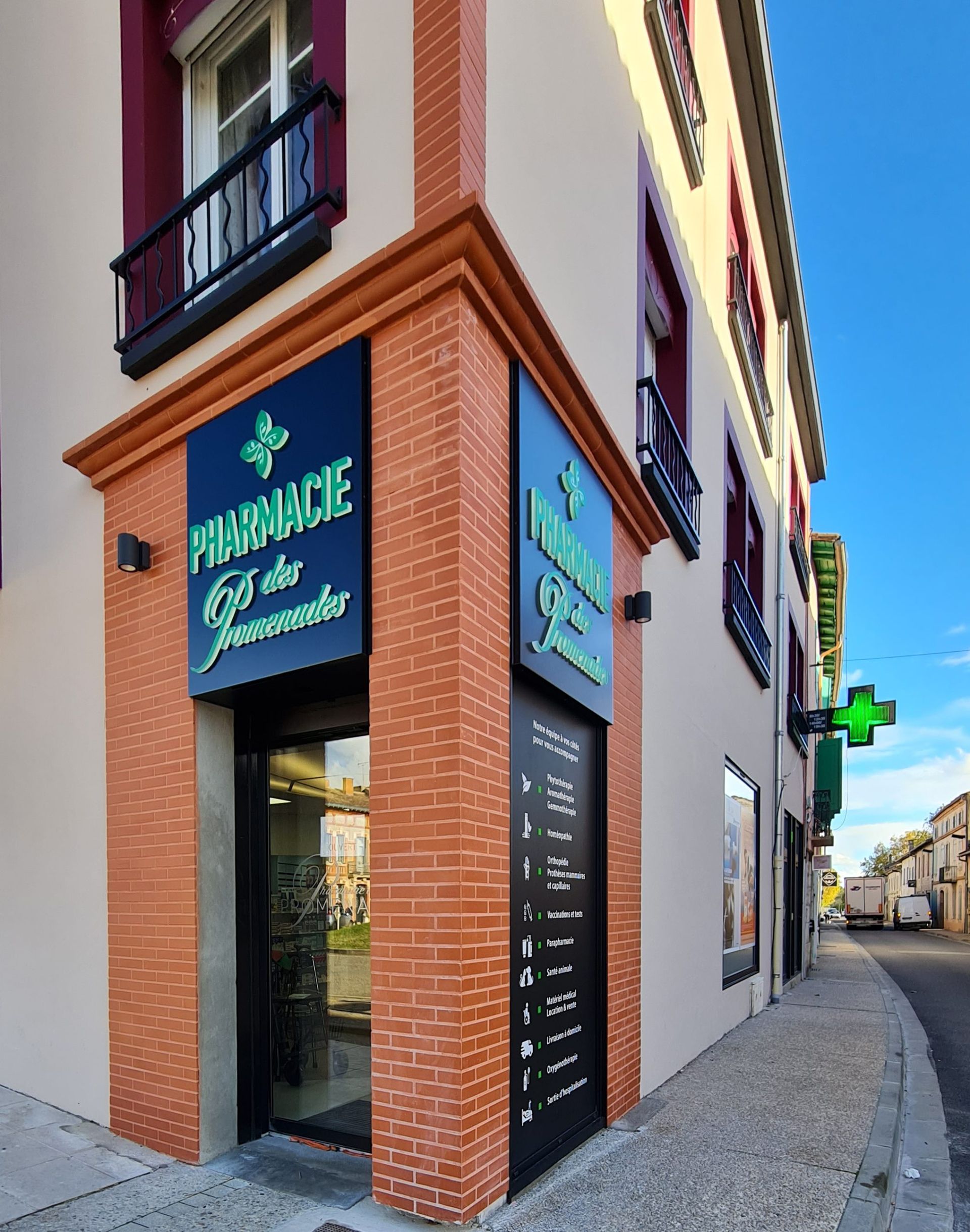 Façade de pharmacie avec éléments en brique, enseigne et vue sur la rue.