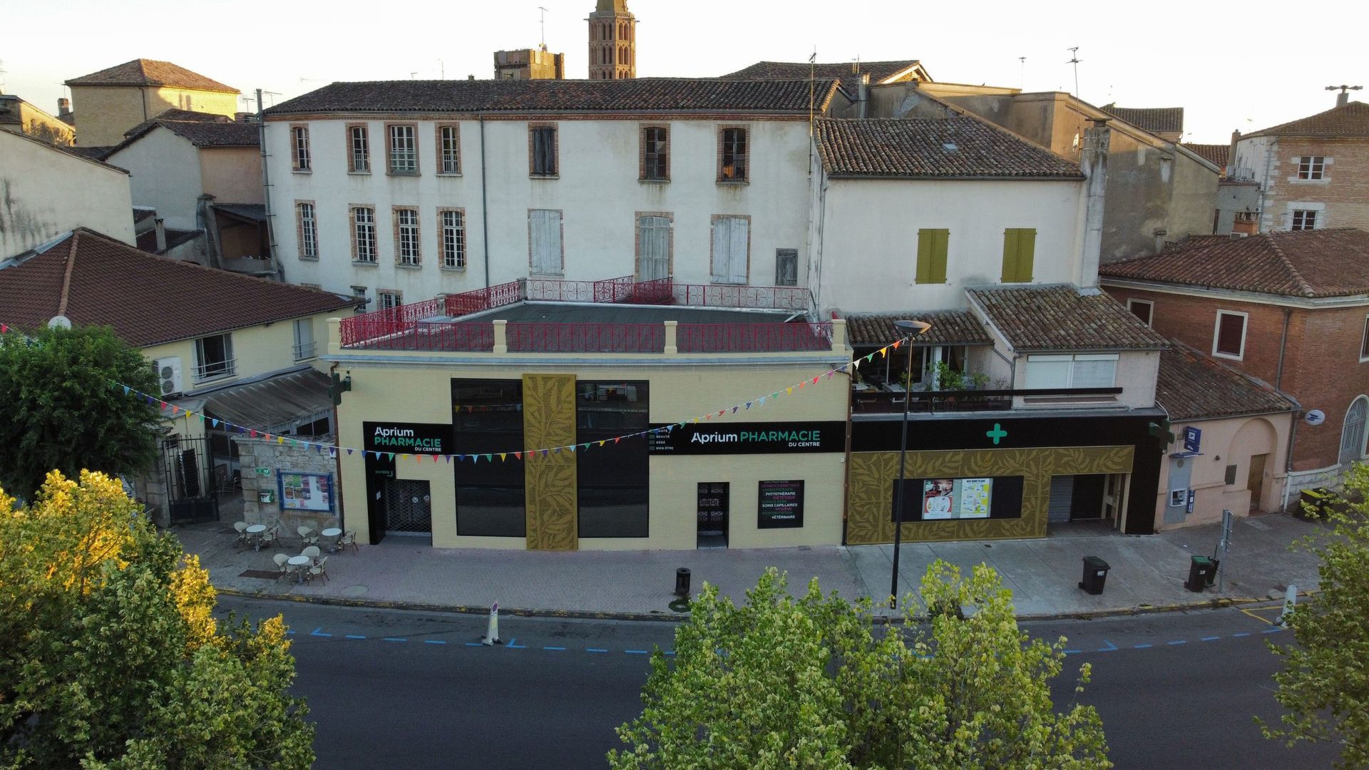 Bâtiments d'une ville européenne, avec un bâtiment moderne au premier plan et une enseigne de pharmacie.