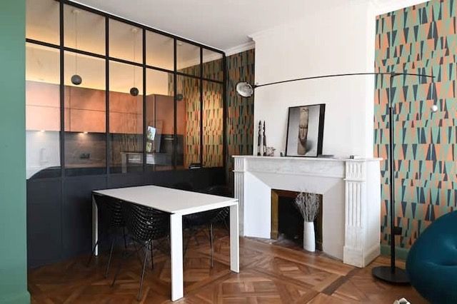 Coin repas avec une table blanche, des chaises noires et une cheminée dans un appartement moderne.