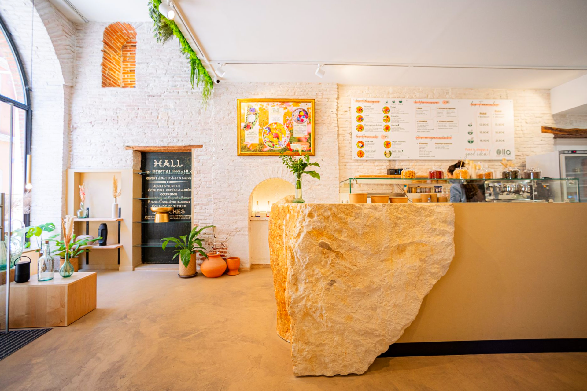 Photo intérieure d'un café avec un comptoir en pierre texturée, des murs en briques et des panneaux de menus.
