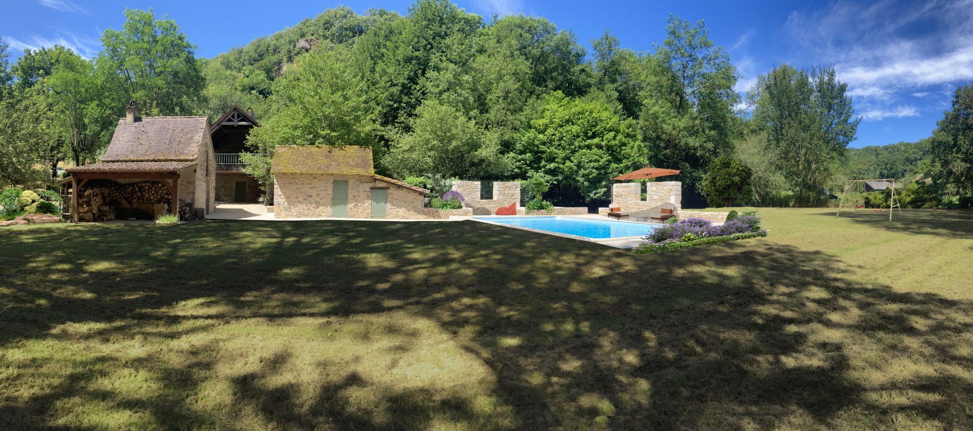 Une maison avec piscine dans un cadre verdoyant luxuriant, avec des arbres et un ciel bleu.