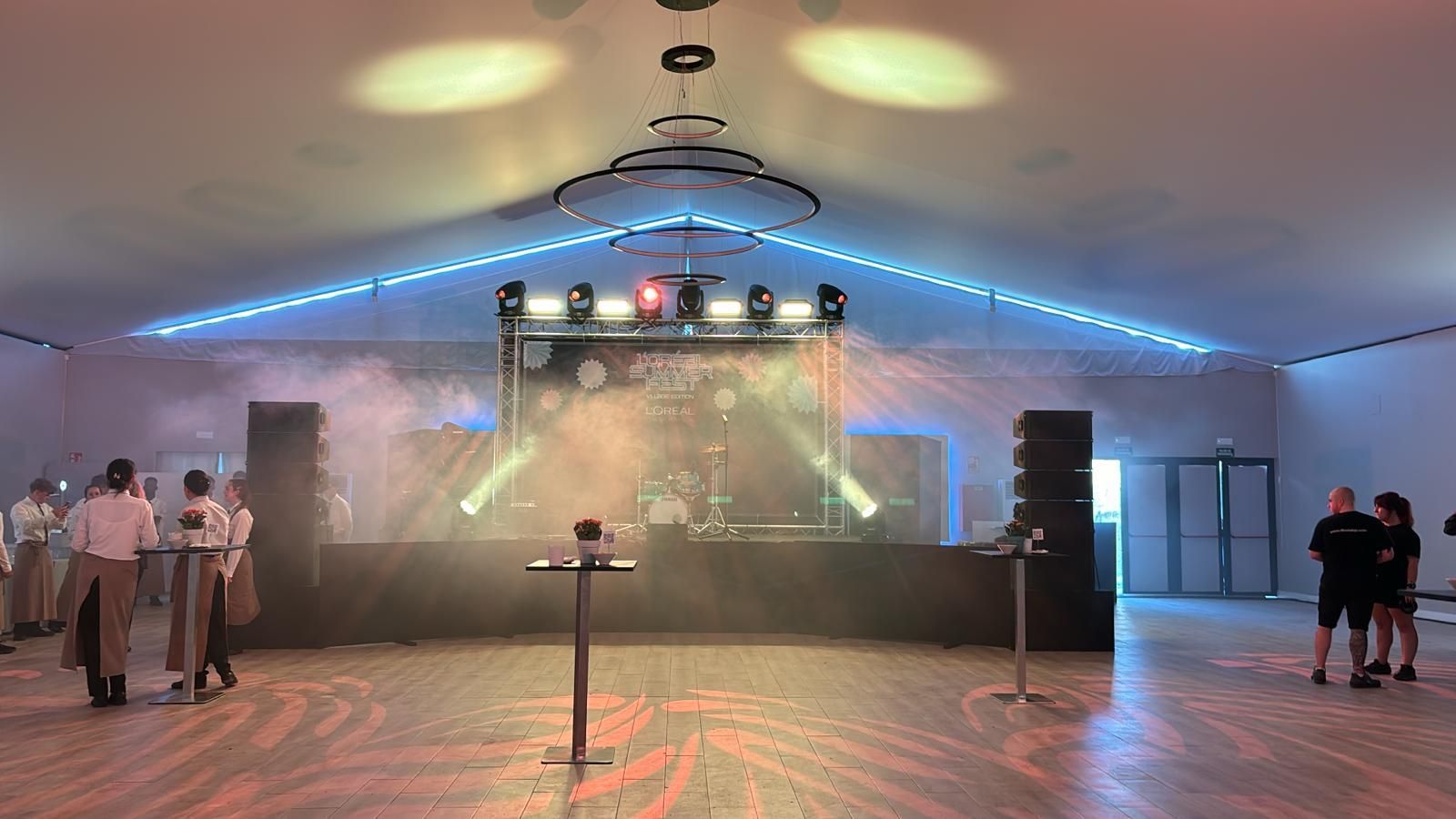 Una sala grande con un escenario y gente parada alrededor de él.