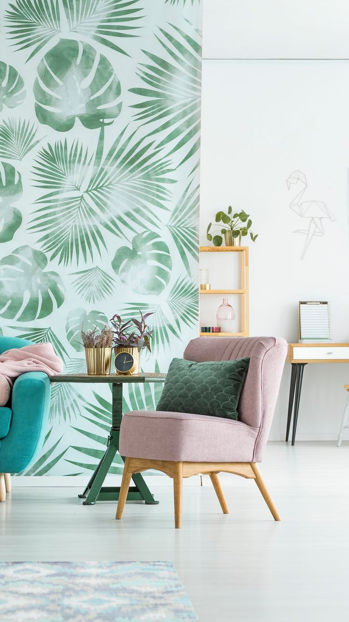 Salon avec papier peint à motifs, chaises bleu sarcelle et rose, petite table et plantes.
