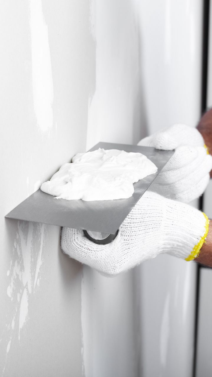 Un maçon applique de l'enduit sur une cloison.