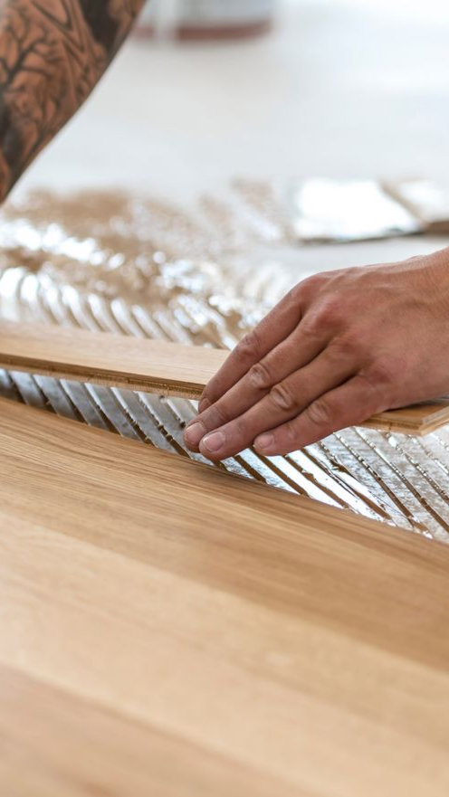 Main d'une personne coupant du bois avec une scie. Gros plan sur la lame et le bois.