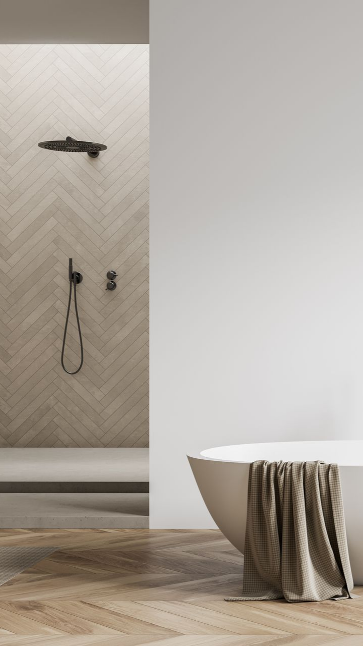 Salle de bains moderne avec baignoire, douche, parquet et serviette drapée sur la baignoire.