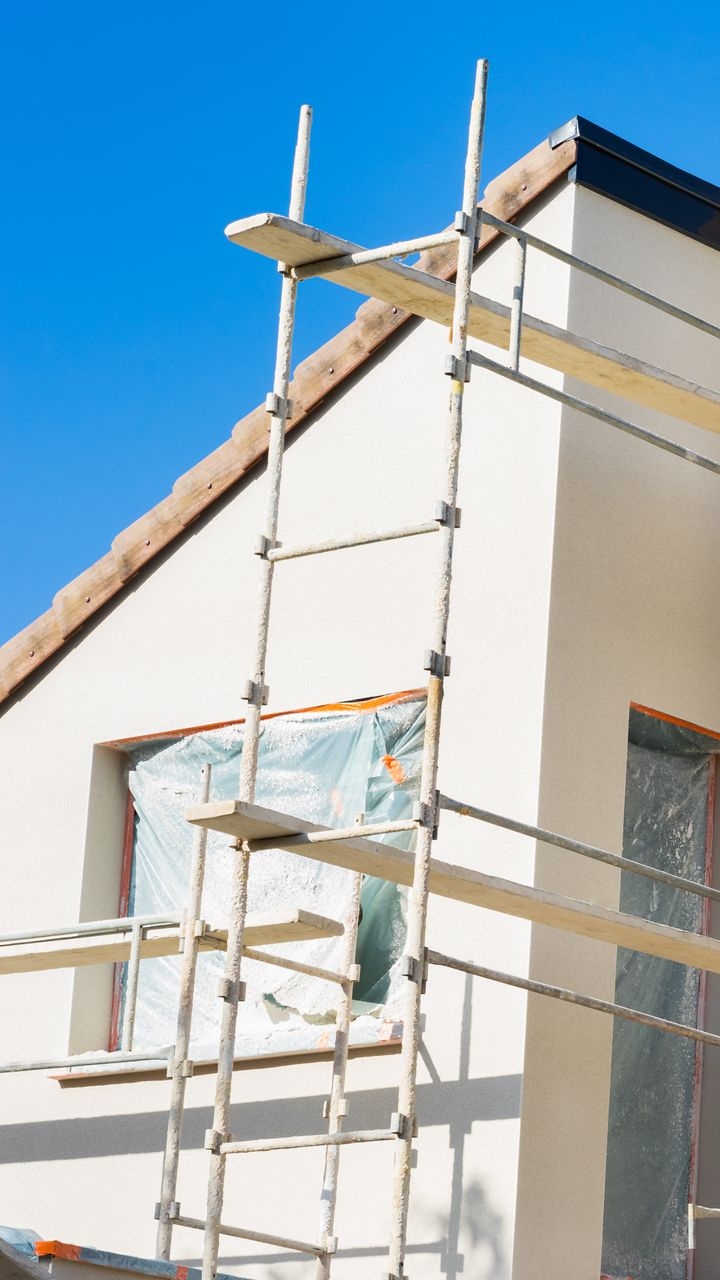 Échafaudage contre une maison aux fenêtres obstruées. Ciel bleu en arrière-plan.