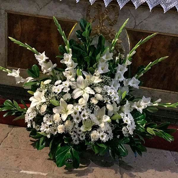 Un ramo de flores blancas reposa sobre un suelo de baldosas.