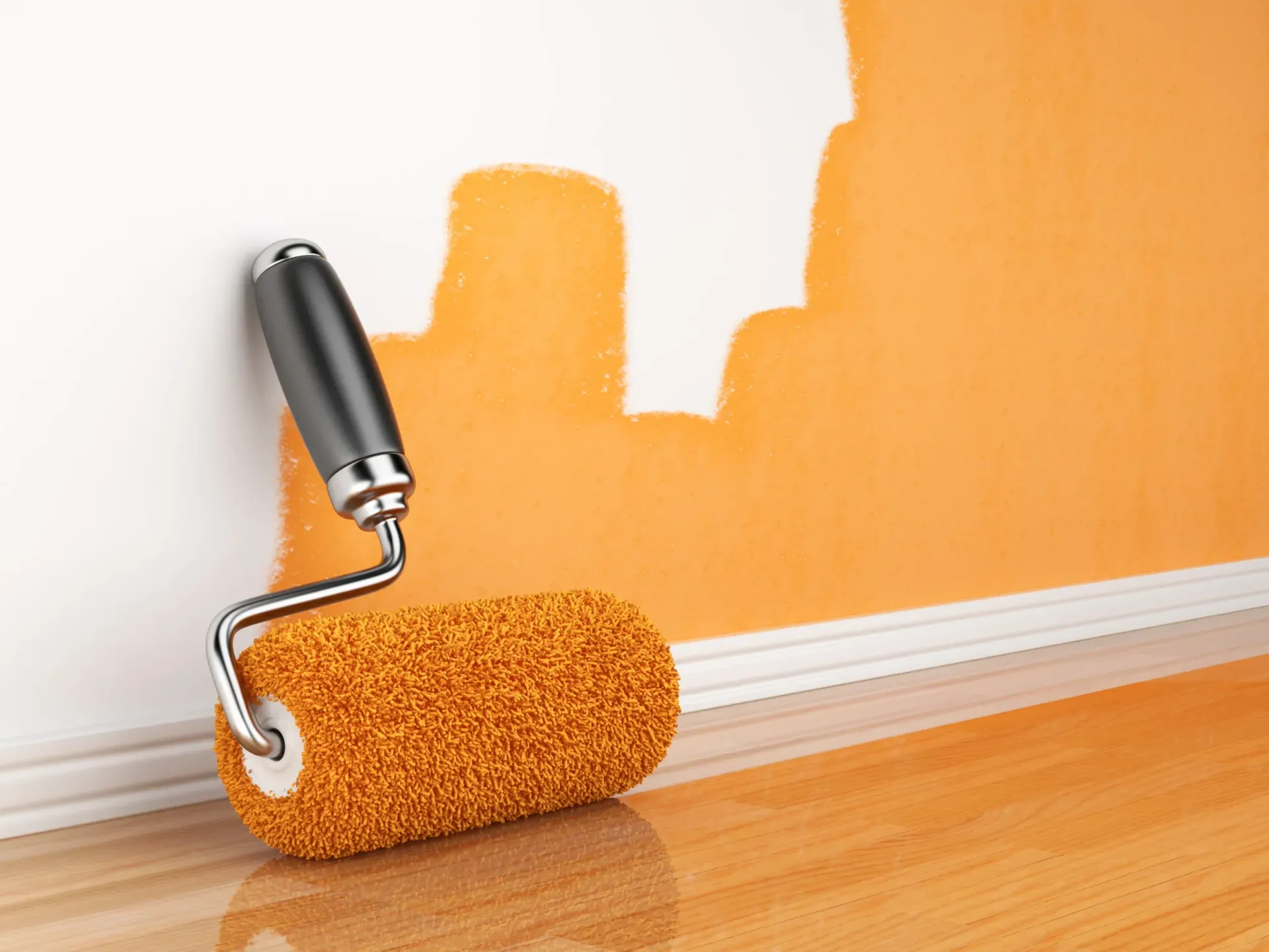 Un rodillo de pintura está colocado sobre un piso de madera frente a una pared naranja.