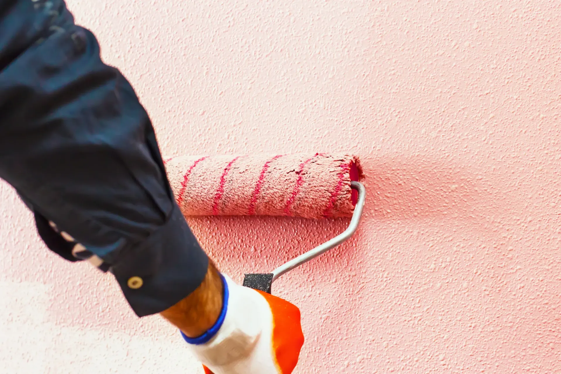 Una persona está pintando una pared con un rodillo de pintura.