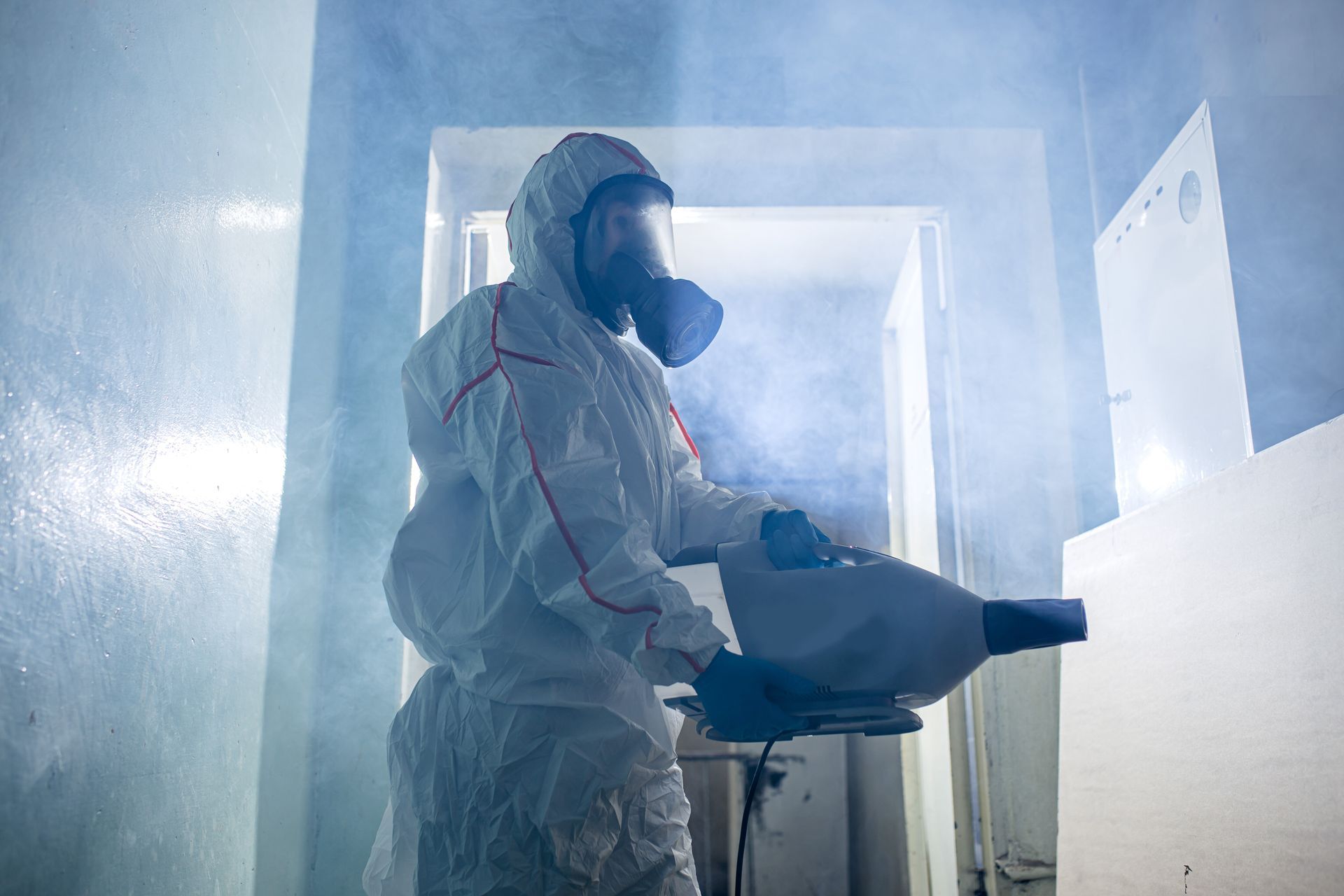 Une personne avec un masque qui désinfecte une pièce