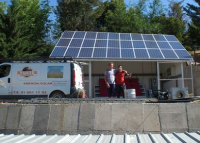 Dos hombres están parados frente a una camioneta con paneles solares en el techo.