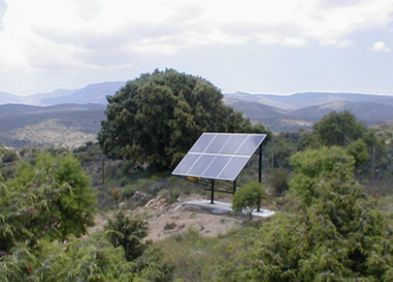 Un panel solar está situado en la cima de una colina en medio de un bosque.