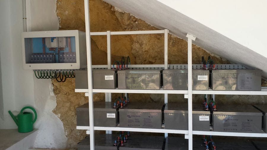 Una regadera verde está junto a un estante con cajas encima.