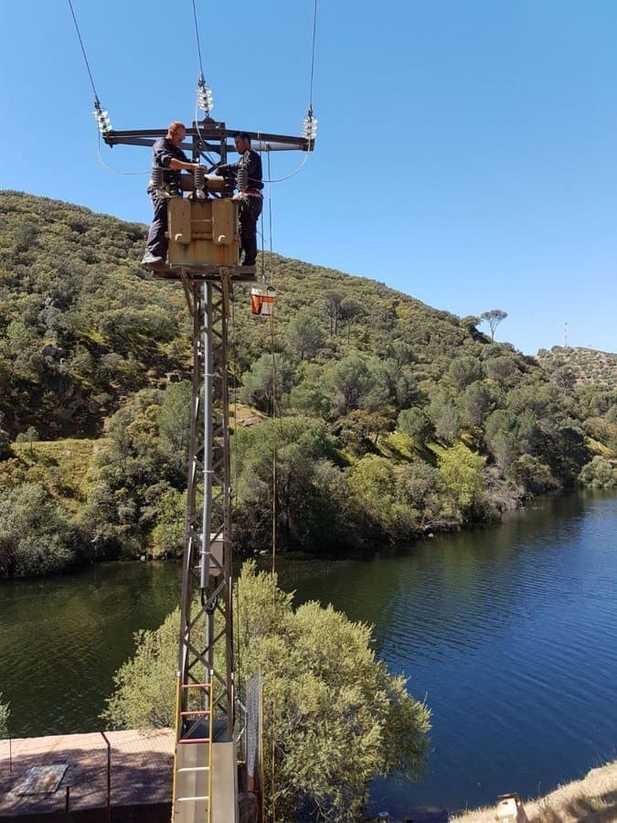 Dos hombres están trabajando en una torre con vistas a un lago.