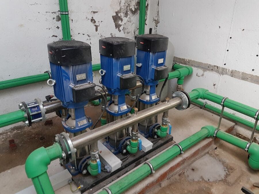 Una habitación con tuberías verdes y tres bombas azules.