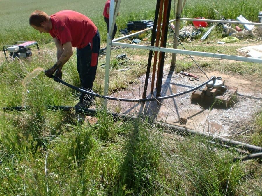 Un hombre con una camisa roja está trabajando en un campo.