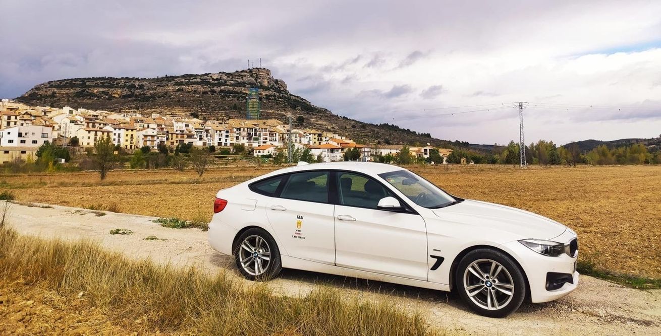Un coche blanco está estacionado al costado de un camino de tierra en un campo.
