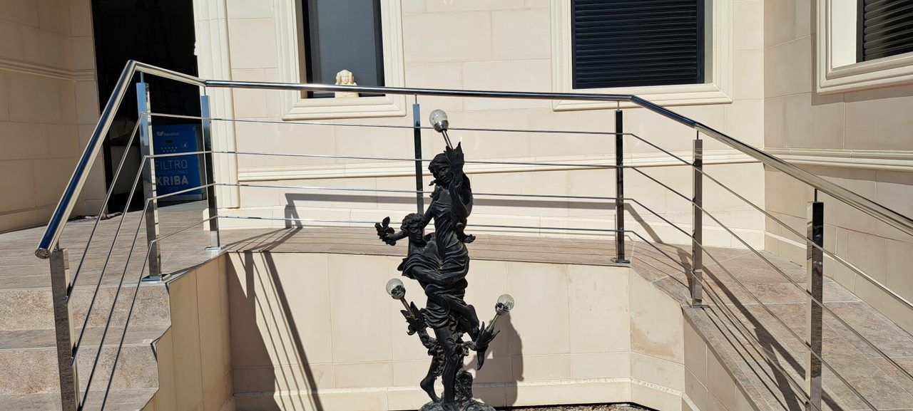 Una escalera con barandilla de acero inoxidable y una estatua en el medio.