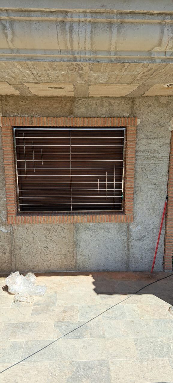 Una pared de ladrillos con una ventana con una reja de metal.