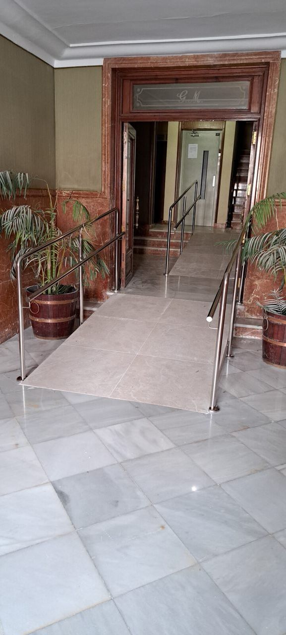 Un pasillo con plantas en macetas y escaleras en un edificio.